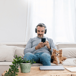 Mann sitzt mit Handy und Hund auf der Couch und macht Homeoffice